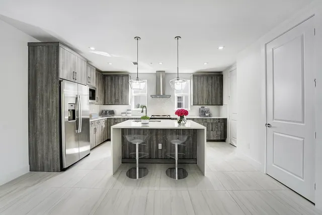 a kitchen with stainless steel appliances a dining table chairs refrigerator and sink