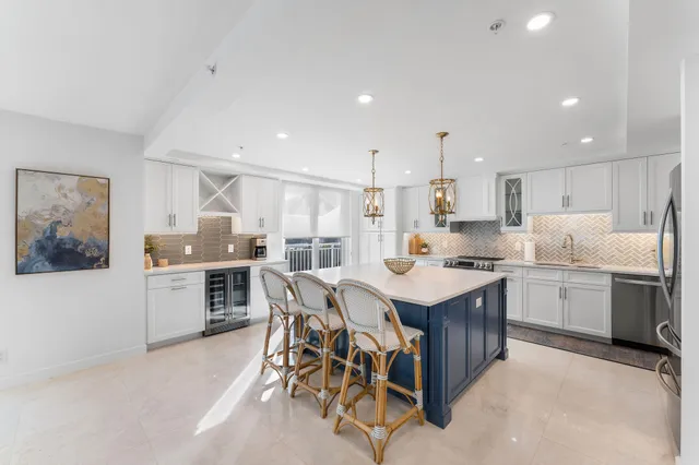 a kitchen with a stove a sink a kitchen island with chairs and wooden cabinets