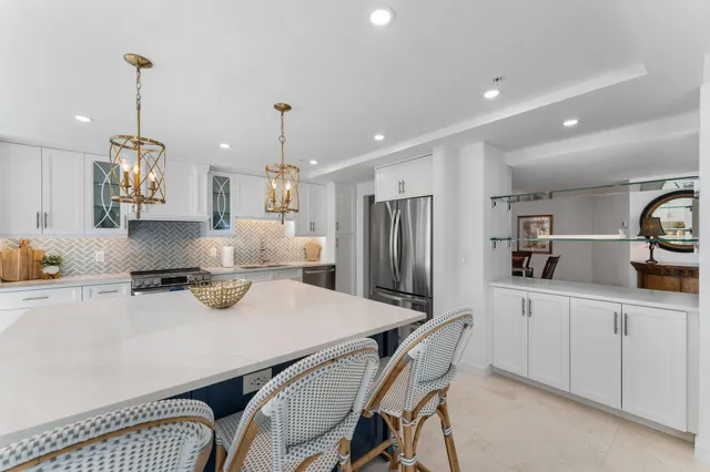 a kitchen with refrigerator a sink a stove and chairs