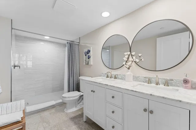 a bathroom with a double vanity sink mirror and toilet