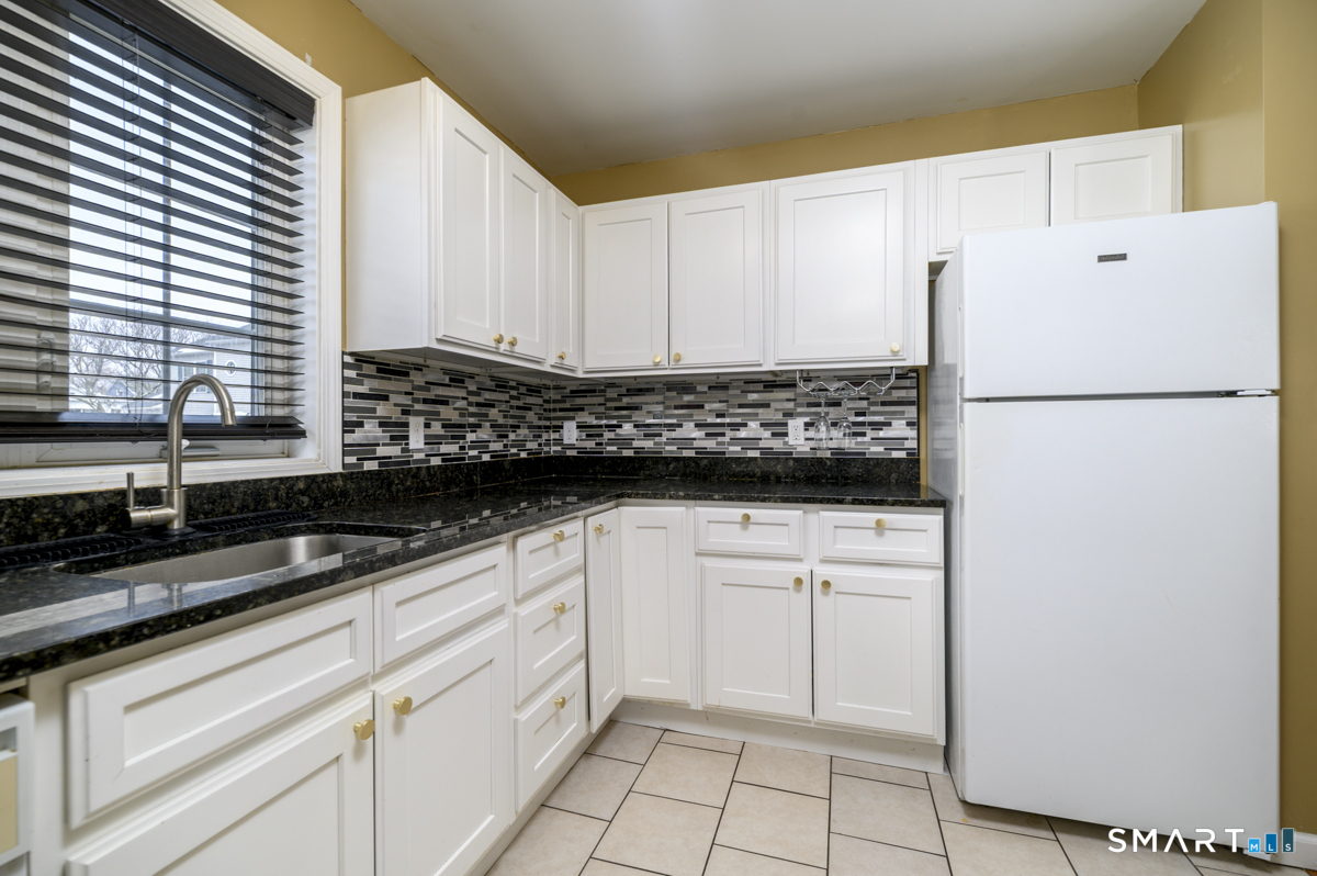 800 Seaview Avenue, Unit 8001 Bridgeport, CT 06607 - Photo 12 of 25 a white kitchen with granite countertop a refrigerator a sink and white cabinets