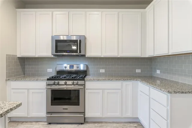 a kitchen with white cabinets and a stove with a sink