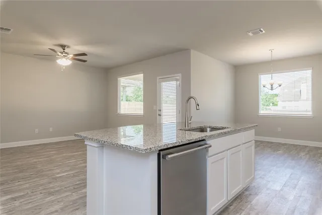 a kitchen with granite countertop cabinets a sink a window and a rug