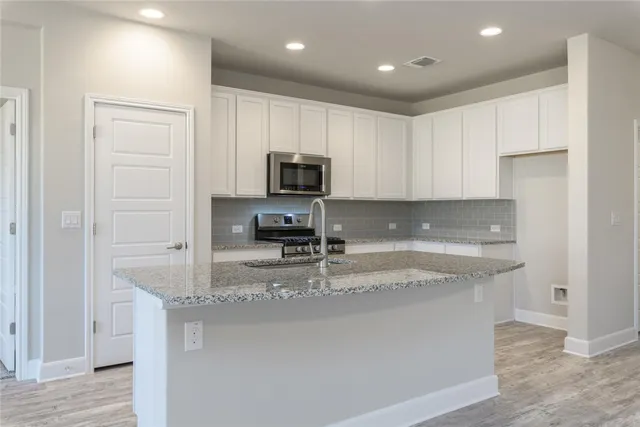 a kitchen with kitchen island granite countertop a sink a counter top space appliances and cabinets