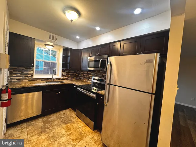 a kitchen with granite countertop stainless steel appliances a refrigerator a sink a stove a microwave and cabinets