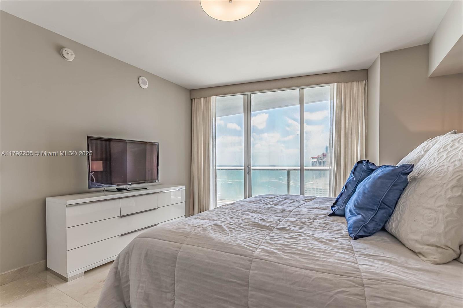 495 Brickell Avenue, Unit 2801 Miami, FL 33131 - Photo 19 of 22 a bedroom with a large bed and a flat tv screen on dresser