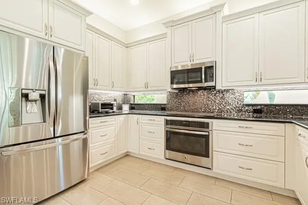 a kitchen with granite countertop white cabinets and stainless steel appliances