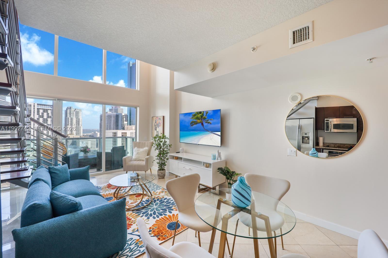 41 Southeast 5th Street, Unit 1505 Miami, FL 33131 - Photo 3 of 16 a living room with furniture a rug and a large window