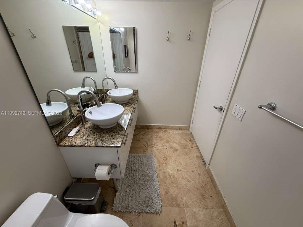41 Southeast 5th Street, Unit 1505 Miami, FL 33131 - Photo 8 of 16 a bathroom with a granite countertop toilet sink and mirror