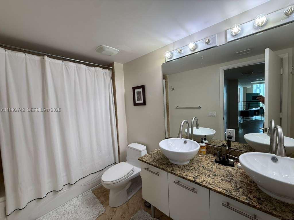 41 Southeast 5th Street, Unit 1505 Miami, FL 33131 - Photo 9 of 16 a bathroom with a granite countertop sink and a mirror