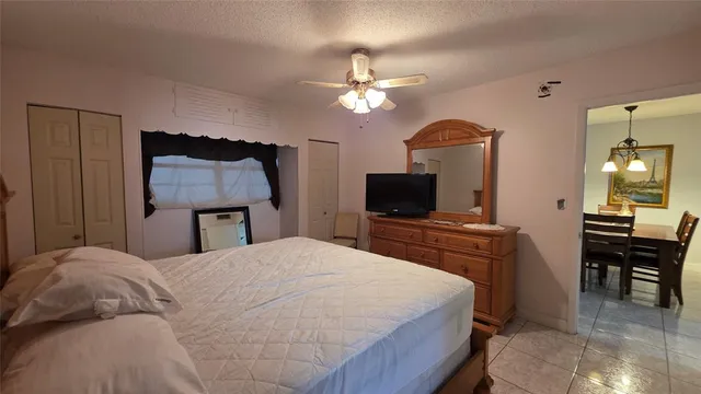 a bedroom with a bed a mirror on dresser and a flat screen tv