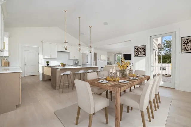 a view of a dining room and livingroom with furniture wooden floor kitchen view and a window