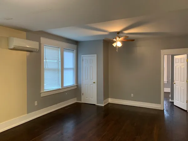 a view of an empty room with wooden floor and a window