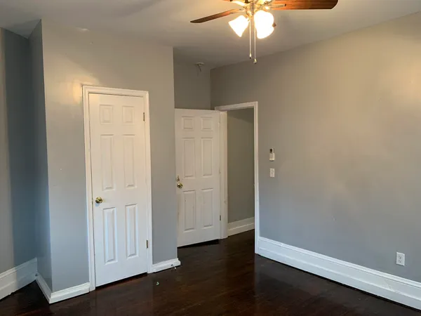 an empty room with wooden floor closet and windows