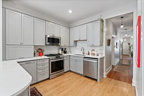 a kitchen with stainless steel appliances granite countertop a stove top oven a sink and white cabinets