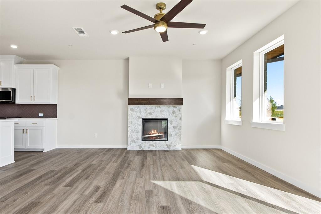 2028 Aldrich Road Celina, TX 75009 - Photo 8 of 40 a view of a livingroom with a fireplace a ceiling fan and wooden floor
