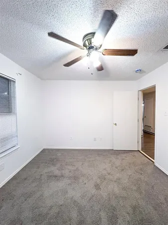 an empty room with a ceiling fan and window