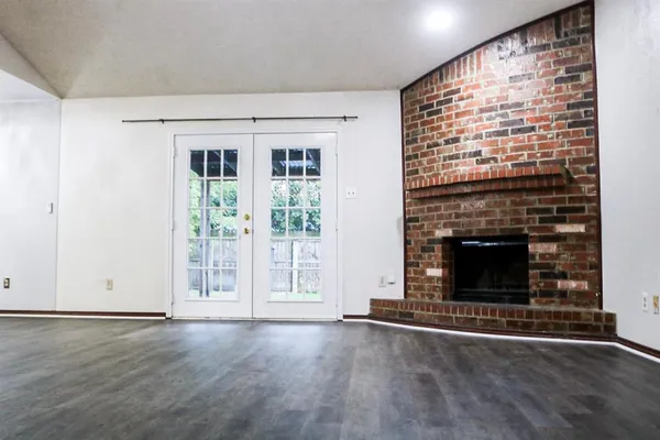 an empty room with wooden floor fireplace and windows