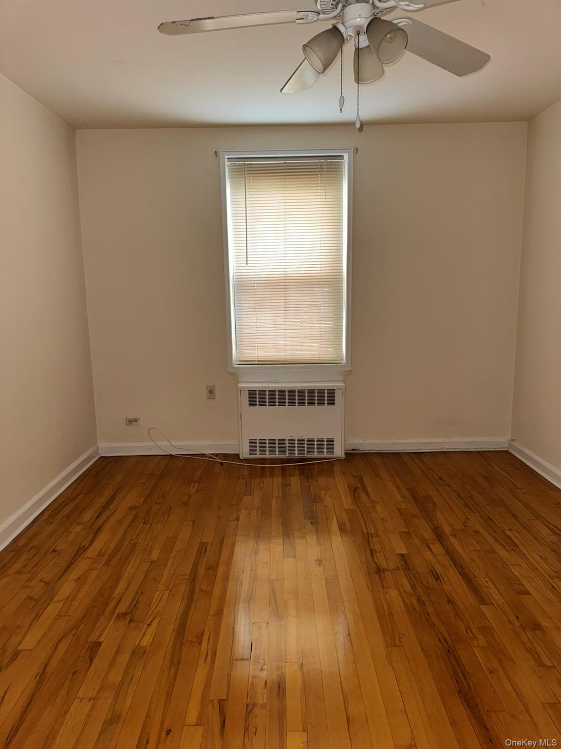88-10 34th Avenue, Unit 2M Queens, NY 11372 - Photo 2 of 12 an empty room with wooden floor and windows