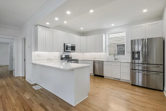 a kitchen with kitchen island a sink a center island stainless steel appliances and a window