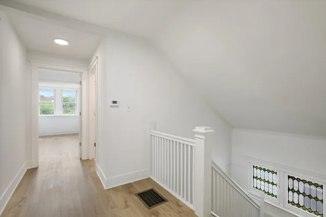a view of a hallway with wooden floor and windows