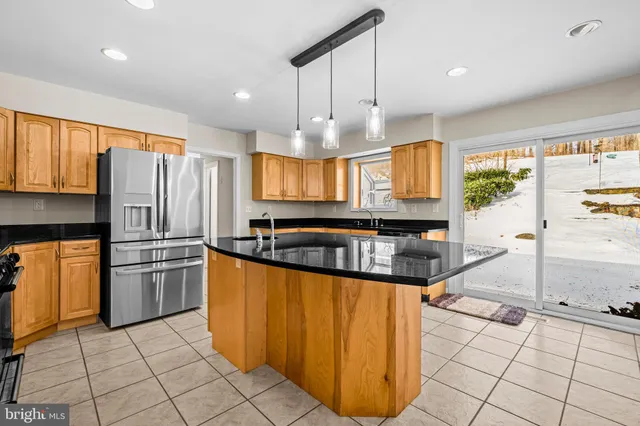 a kitchen with stainless steel appliances kitchen island granite countertop a refrigerator and a stove top oven