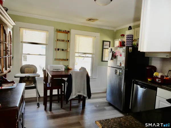 a kitchen with stainless steel appliances a refrigerator a stove a dining table and chairs with wooden floor