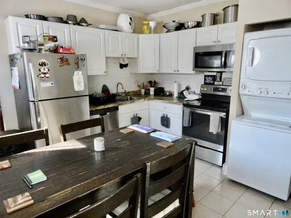 a kitchen with a dining table chairs and refrigerator