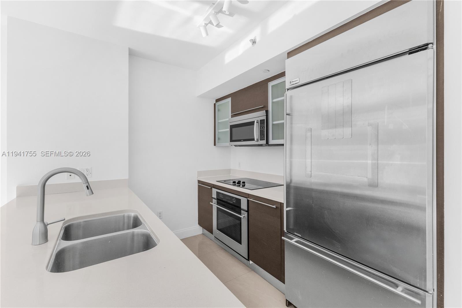 55 Southeast 6th Street, Unit 1202 Miami, FL 33131 - Photo 11 of 45 a kitchen with a sink and a refrigerator