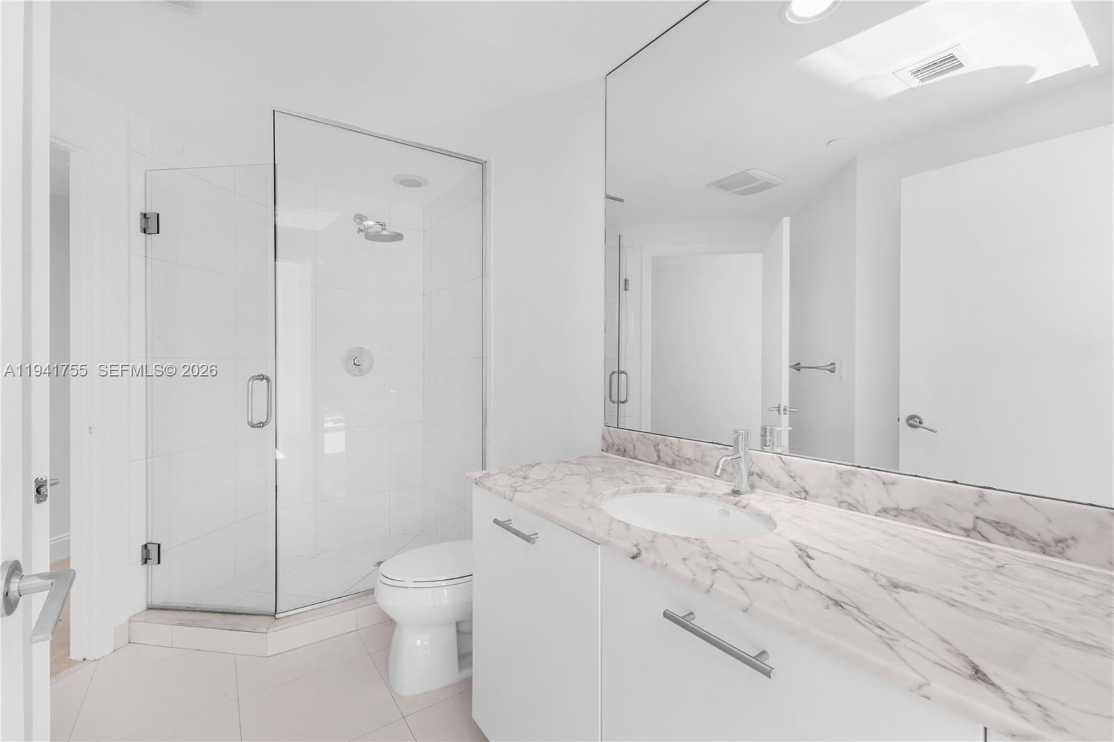 55 Southeast 6th Street, Unit 1202 Miami, FL 33131 - Photo 24 of 45 a bathroom with a granite countertop sink a toilet and shower