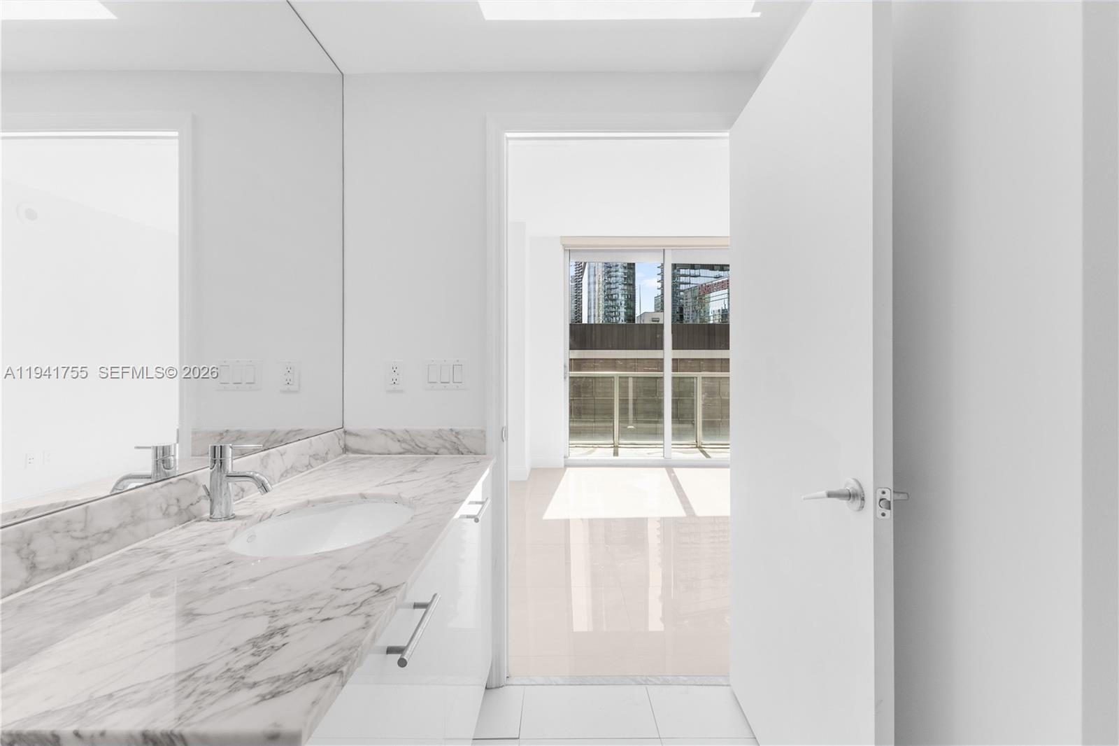 55 Southeast 6th Street, Unit 1202 Miami, FL 33131 - Photo 25 of 45 a bathroom with a granite countertop sink and a mirror