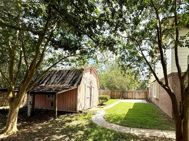 a backyard of a house with large trees and outdoor seating