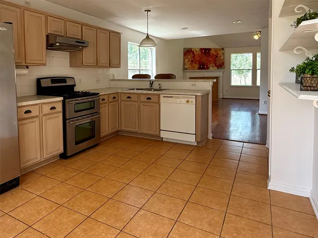 a kitchen with stainless steel appliances a stove a sink and white cabinets