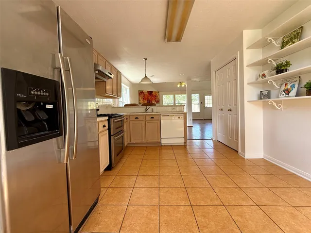 a large kitchen with stainless steel appliances granite countertop a refrigerator and a stove top oven