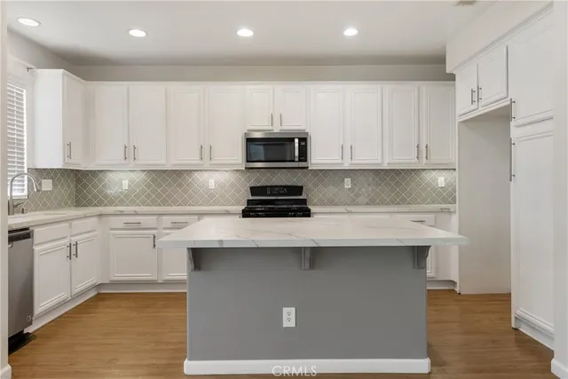 a kitchen with stainless steel appliances granite countertop a stove a sink dishwasher and a refrigerator with wooden cabinets
