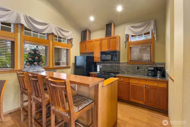 a kitchen with stainless steel appliances granite countertop a sink a stove a dining table and chairs