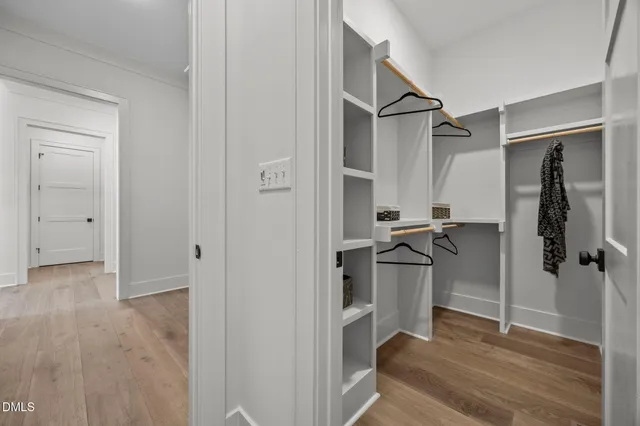 a view of an empty room with wooden floor and kitchen space