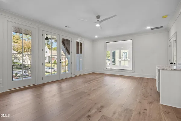 a view of an empty room with window and wooden floor