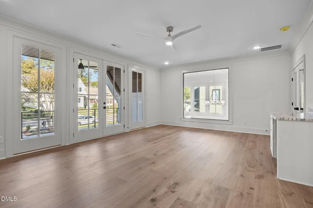 a view of an empty room with window and wooden floor