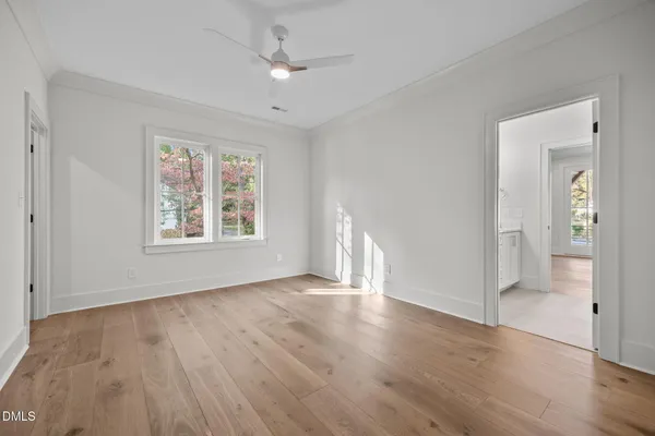 a view of an empty room with wooden floor and windows