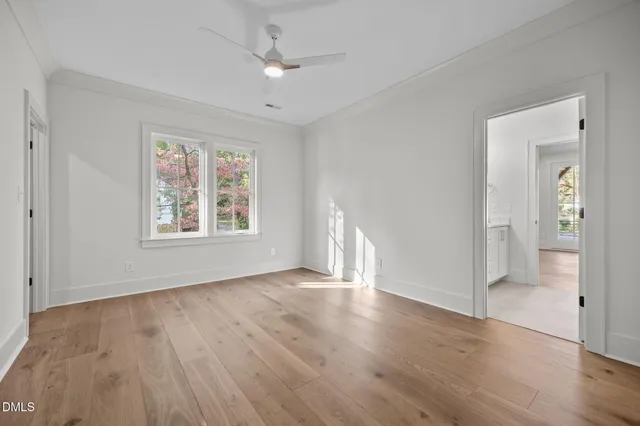 a view of an empty room with wooden floor and windows
