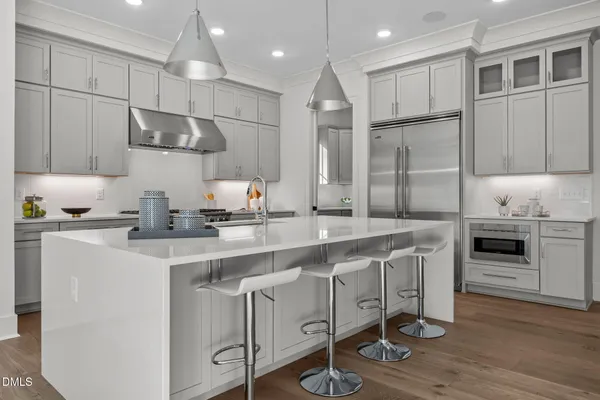 a kitchen with stainless steel appliances granite countertop a sink a stove a refrigerator and island with wooden floor