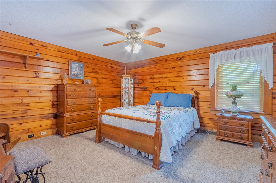 911 State Rd S-4-203 Belton, SC 29627 - Photo 22 of 49 A well-lit bedroom featuring rich wood paneling and a textured carpet.