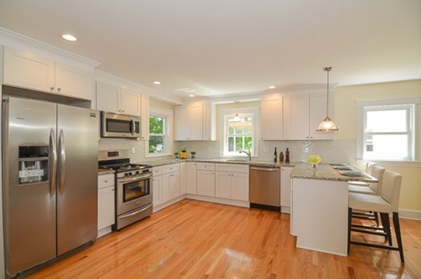 a kitchen with a sink wooden floor and stainless steel appliances