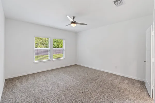 an empty room with windows and ceiling fan