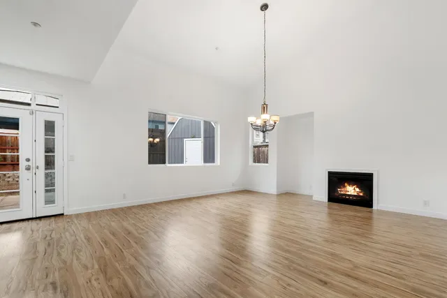 a view of a livingroom with a kitchen island stainless steel appliances a wooden floor and a chandelier