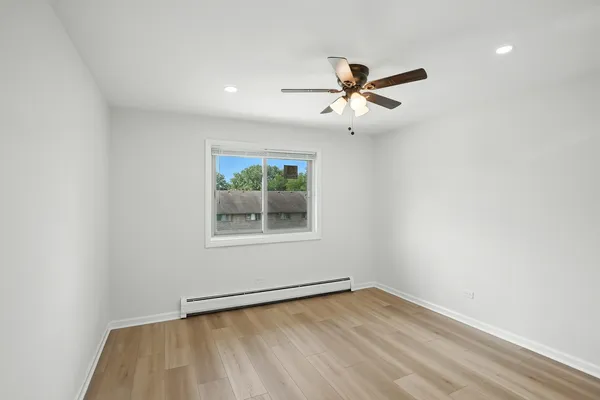 an empty room with a window and ceiling fan