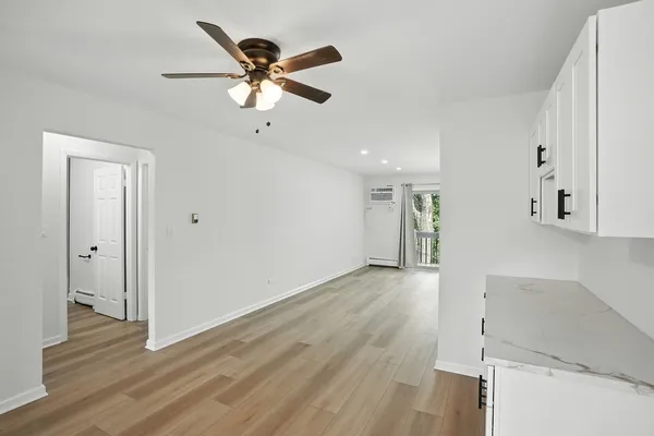 a view of an empty room with wooden floor and a ceiling fan