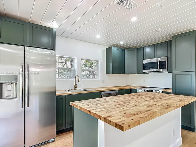 a kitchen with kitchen island a sink stainless steel appliances and cabinets