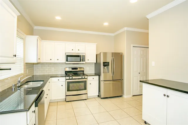a kitchen with stainless steel appliances granite countertop a refrigerator a stove and a sink with wooden floor